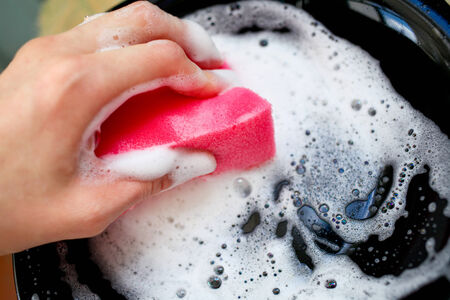 hands with sponge washing dishes in kitchen sinkの写真素材