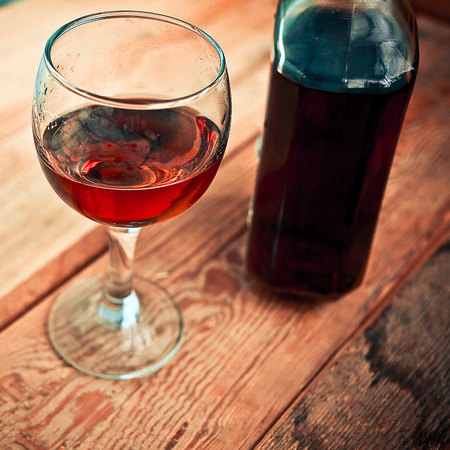 bottle and glass of cognac with ice on a wooden backgroundの写真素材