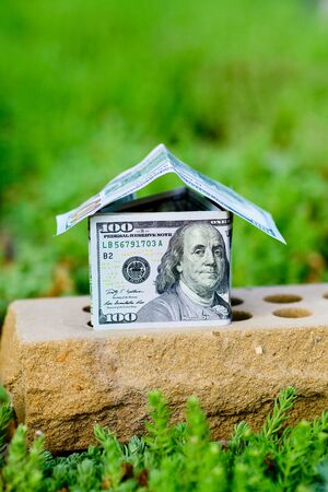 A dollar bill house on a brickの写真素材