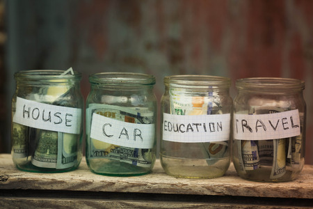 Glass jars with dollars and text: house,car, travel, educationの写真素材