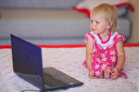 Baby looking thoughtfully into the laptop.