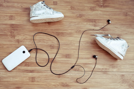 Children's footwear and the smartphone on a wooden background