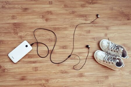 Children's footwear and the smartphone on a wooden backgroundの写真素材