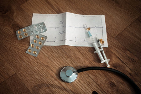 Stethoscope, cardiogram, tablets and syringes on a wooden background.Medicine concept.