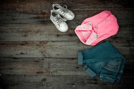 Fashionable children's jeans, blouse and footwear on a wooden backgroundの写真素材