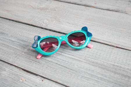 Beautiful children's blue sunglasses on a white wooden backgroundの写真素材