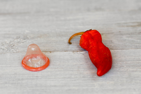 Condom and red pepper on a white wooden backgroundの写真素材