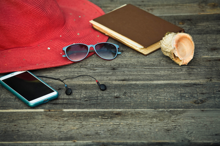 A hat, smartphone, a book as well of wooden backgroundの写真素材