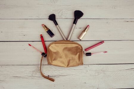 Make-up bag with products spilling out on a wooden backgroundの写真素材