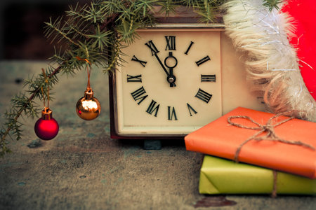 Gift box and clock with christmas baubles on wooden background