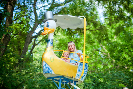 Mother and the daughter ride a swing in the beautiful park. Attraction.の写真素材