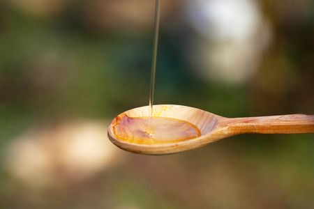 Extra virgin olive oil pouring over a spoonの写真素材