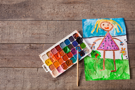 The children is drawing paints on a wooden background.の写真素材