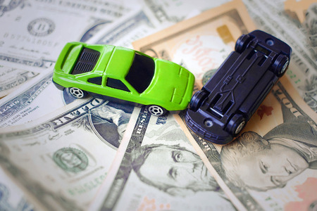 Toy cars in acciden on a background of 100 dollar billsの写真素材