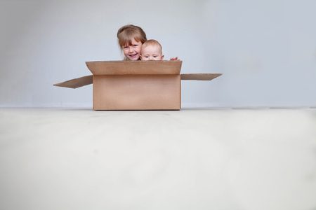 The girl with the little brother sit in a box. The place for the text, copy spaceの写真素材