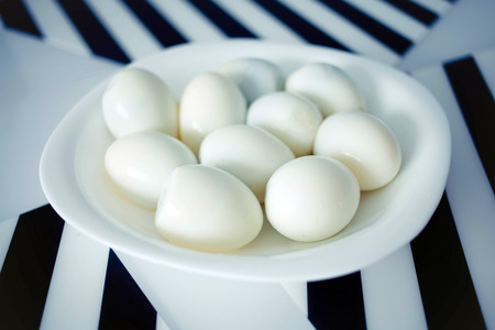 The chicken boiled peeled eggs on a plate with a white and black background.の写真素材
