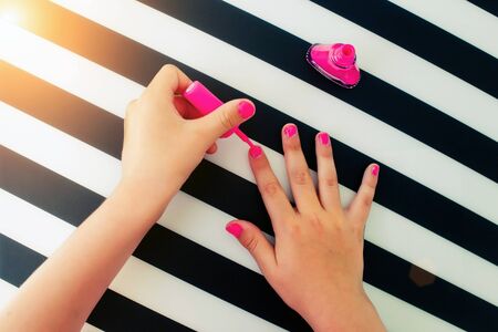 The little girl paints nails pink nail varnish. Top viewの写真素材