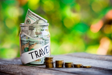 Glass jar with dollars and the word travel paper label. Travel budget concept. Travel money savings...