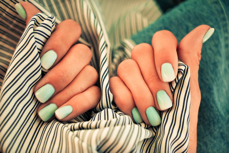 Close up nails with a gradient blue manicure on a jeans background. Top View