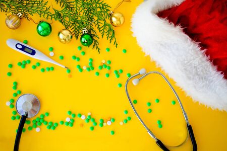 Stethoscope , thermometer, pills and christmas balls on yellow background. Happy New Year for health care and medical banner/calendar cover. Top view  , copy space. の写真素材