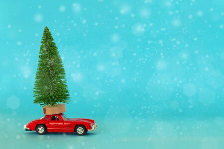 Krasnodar, Russia - December 10, 2019: Red toy car with a christmas tree on the roof, blue background. Copy space . Concept new year.のeditorial素材