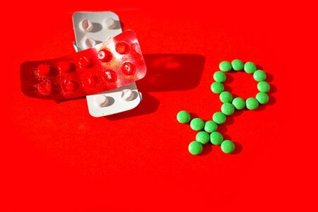 Female health. Gender symbol made from green pills or tablets  on a red background.の写真素材