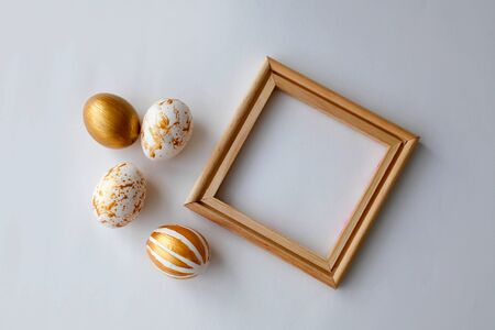 Easter eggs on a gold  and wooden frame background on a white background. Celebration. Toned photo. の写真素材