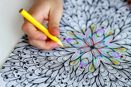 Close-up of girls hands draw with crayons in anti-stress coloring.の写真素材