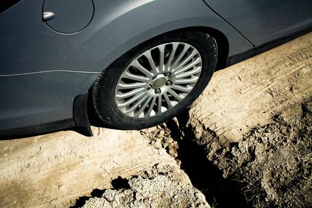 Close-up of a car wheel stuck in a pit. Big ditch on a rural road.の写真素材
