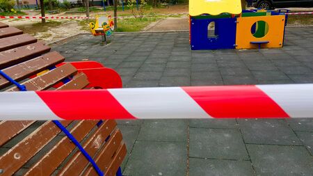 Children is playground closed and wrapped in alarm caution tape for global coronavirus quarantine.No children on playgrounds. Prevention of coronavirus COVID-19.の写真素材