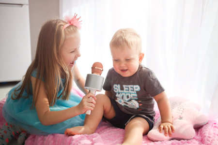 Brother and sister sing into the microphone. Karaoke at home, children is entertainmentの写真素材