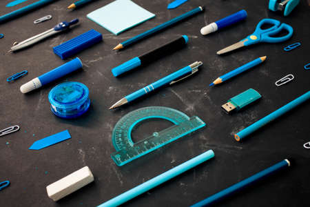 Back to school, stationery in blue on the background of the school board and wood background. Flat lay, top view.の写真素材