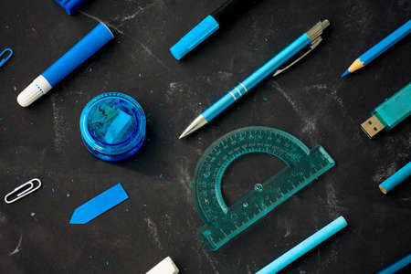 Back to school, stationery in blue on the background of the school board and wood background. Flat lay, top view.の写真素材