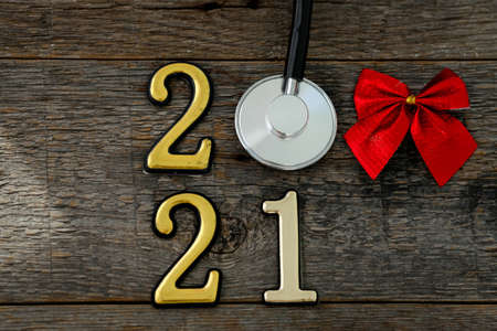 Stethoscope with 2020 number and red bow on wooden background. Happy New Year for health care. Top view, copy space.の写真素材