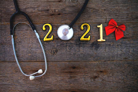 Stethoscope with 2020 number and red bow on wooden background. Happy New Year for health care. Top view, copy space.の写真素材