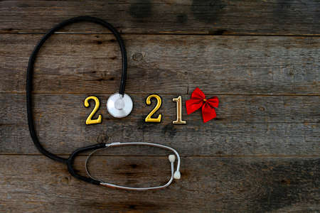 Stethoscope with 2020 number and red bow on wooden background. Happy New Year for health care. Top view, copy space.の写真素材