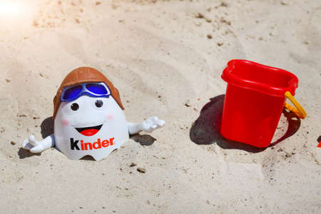 Russia - July 19, 2020: Kinder Surprise Kinderino Mascot Toys and paddles in the sandのeditorial素材