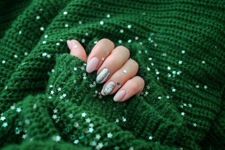Beautiful female hand in a green sweater with Christmas nail design. Nail design, manicure with chimes pattern. Shellac, gel polish.の写真素材