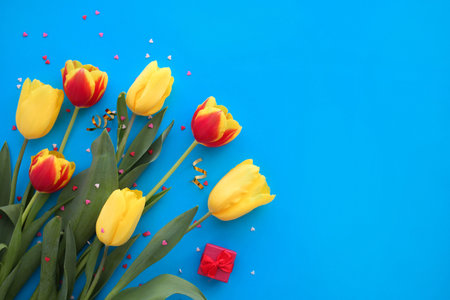 Bouquet of yellow and red tulips and small hearts on a blue background. International Women is Day - 8 March. Valentines Day. Copy space.の写真素材