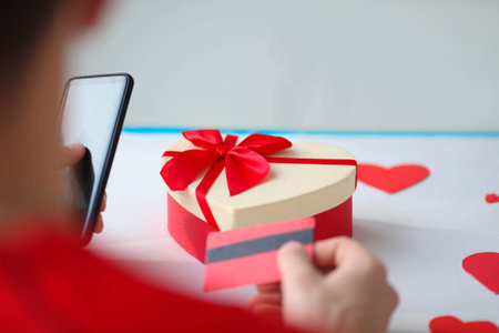 A man holds a mobile phone and a credit card in his hands. Online shopping. Valentines Day gifts....