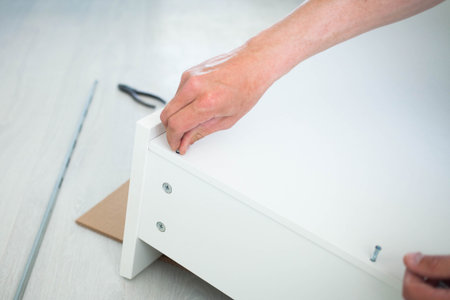 Close up of man hand, furniture assembler make flat pack white furniture assembly service at home.