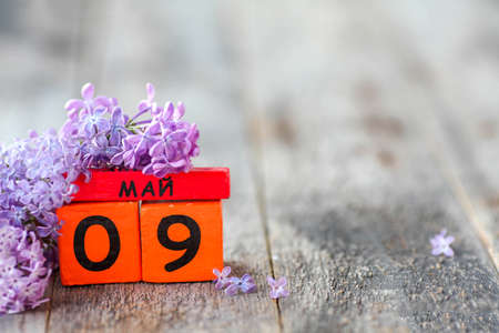 Wooden calendar with Russian text May 9 and a bouquet of lilacs on a wooden background. Victory Day. Copy space.の写真素材
