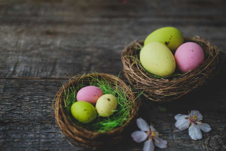 Easter quail painted eggs in a nest and spring flowers on a wooden background. An Easter card with a copy of the place for the text. Top view.の写真素材
