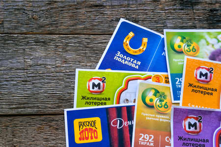 Krasnodar, Russia, April 10, 2021: Various Russia lottery tickets on wooden background. Russian lotto. Gambling. Copy space. Housing lottery, golden horseshoe, Russian lotto.のeditorial素材