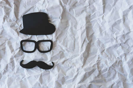 Happy Fathers Day sticker, black hat, glasses and mustache on crumpled paper background. Hipster objects. Father's Day is a holiday. Design Blank space for an inscription.の写真素材
