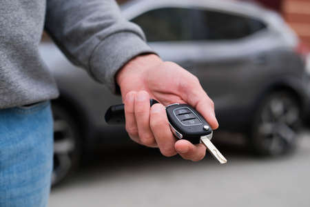 Man in front of the new car and holding keys. Salesman is carrying the car keys delivered to the customer at the showroom with a low interest offer. Rent, credit, insurance, car purchase. Copy spaceの写真素材