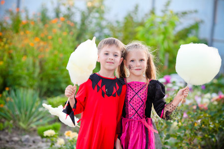 Little boy and girl in costumes of a witch and an executioner for Halloween. Children holding cotton candy. Copy spaceの写真素材