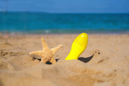 Spray with sunscreen and starfish on the beach. Summer, sea, vacation, sun protection.の写真素材