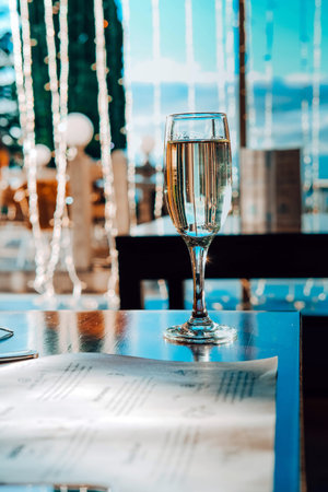 A glass of champagne in the table against the background of the bokeh of a night restaurant. Nightclub, celebration, christmas.の写真素材