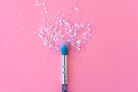 Makeup brush and shiny pink sequins on a pink background. Festive magic makeup concept. Template for design, top view Flat Lay Copy space.の写真素材